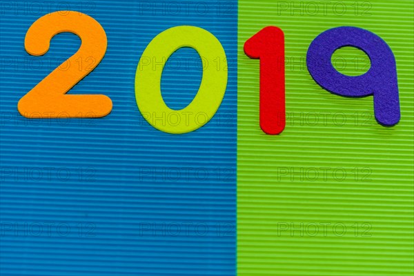 The numbers 2019 made of felt of different colors photographed on blue and green corrugated background