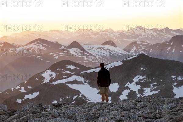 Mountaineer enjoying the view, mountain panorama at the summit of Skala at sunset, Loen, Norway, Europe