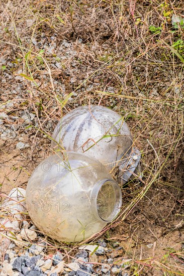 Two round glass light covers laying outside on ground