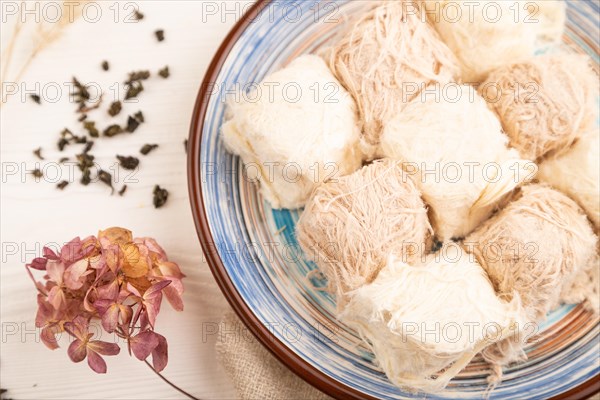Traditional arabic sweets pishmanie and a cup of green tea on white wooden background and linen textile. top view, flat lay, close up