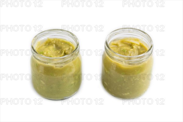 Baby puree with vegetable mix, broccoli, tomatoes, cucumber, avocado infant formula in glass jar isolated on white background. Side view, close up, artificial feeding concept