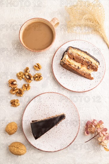 Chocolate biscuit cake with caramel cream and walnuts, cup of coffee on gray concrete background. top view, flat lay, close up