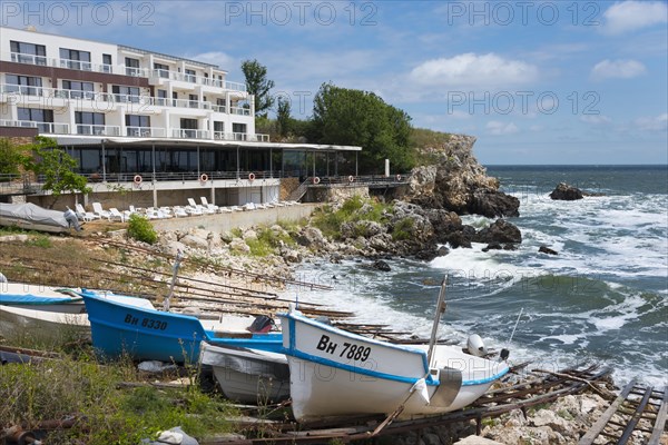 A coastal hotel overlooking the moving sea, surrounded by boats and rocky landscape, harbour and hotel, Tyulenovo, Shabla, Dobrich, Black Sea, Bulgaria, Europe