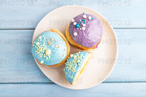 Purple and blue glazed donut on blue wooden background. top view, flat lay. Breakfast, morning, concept