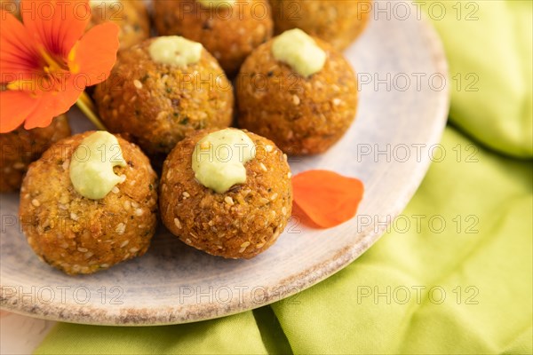Falafel with guacamole on white concrete background and green linen textile. Side view, close up, selective focus