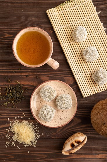 Japanese rice sweet buns mochi filled with pandan and coconut jam and cup of green tea on brown wooden background. top view, flat lay, close up