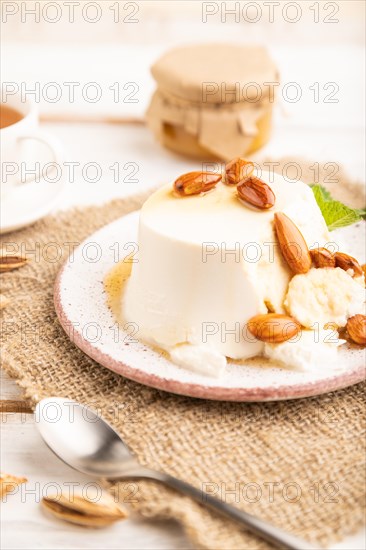 Ricotta cheese with honey and almonds on white wooden background and linen textile. side view, close up, selective focus