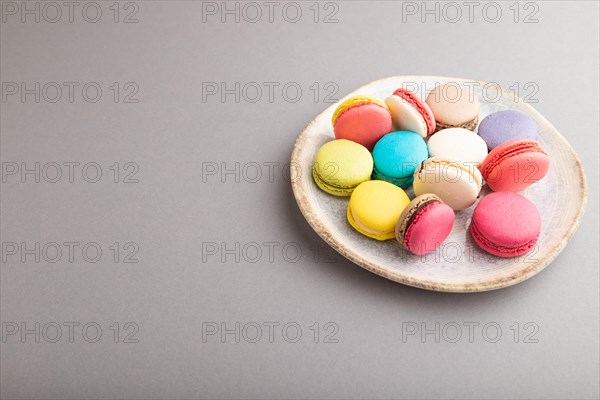 Multicolored macaroons on ceramic plate on gray pastel background. side view, close up, still life, copy space. Breakfast, morning, concept