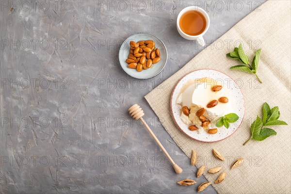 Ricotta cheese with honey and almonds on gray concrete background and linen textile. top view, flat lay, copy space