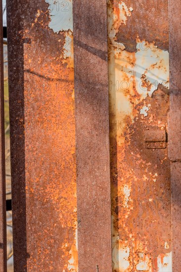 Side view of old electrical switch box inside rusty metal utility box security cage