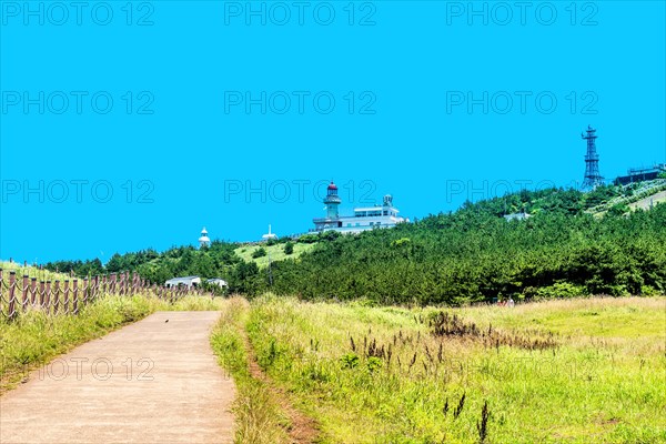 Single lane concrete road leading to lighthouse in background. Located on Udo island, South Korea, Asia