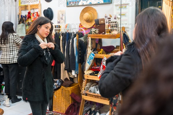 Young and beauty woman trying on a jacket in a clothing store during sales