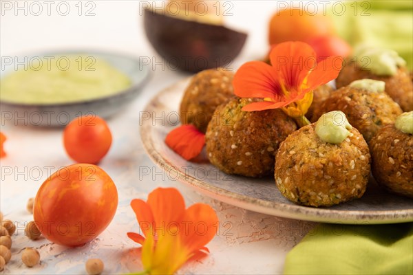 Falafel with guacamole on white concrete background and green linen textile. Side view, close up, selective focus