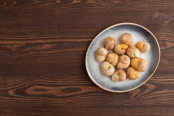 Grape (Burgundy) snails with butter and cheese on brown wooden background. Top view, flat lay, copy space