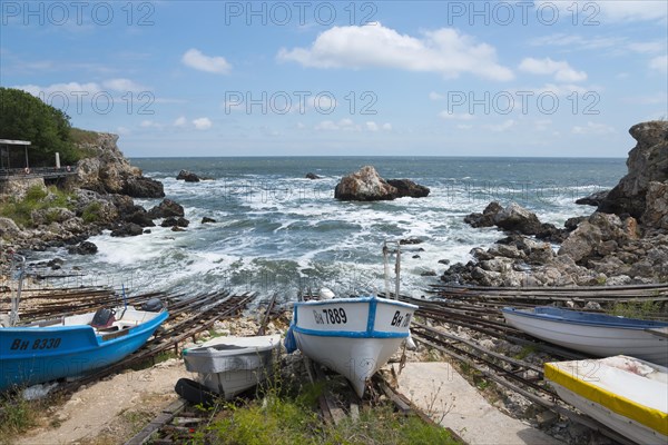 Boats on a coastline with rough seas and rocky outcrops in the background, harbour, Tyulenovo, Shabla, Dobrich, Black Sea, Bulgaria, Europe