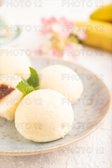 Japanese rice sweet buns mochi filled with jam and cup of coffee on a gray concrete background. side view, close up, selective focus