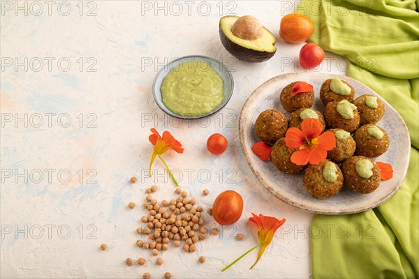 Falafel with guacamole on white concrete background and green linen textile. Side view, copy space