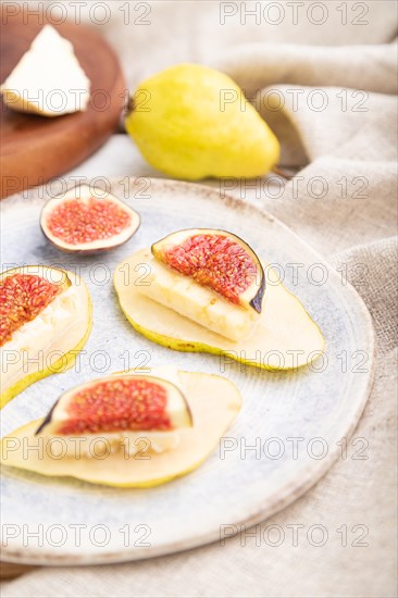 Summer appetizer with pear, cottage cheese, figs and honey on a white wooden background and linen textile. Side view, close up, selective focus
