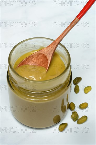 Pistachio cream in jar with spoon, pistachios