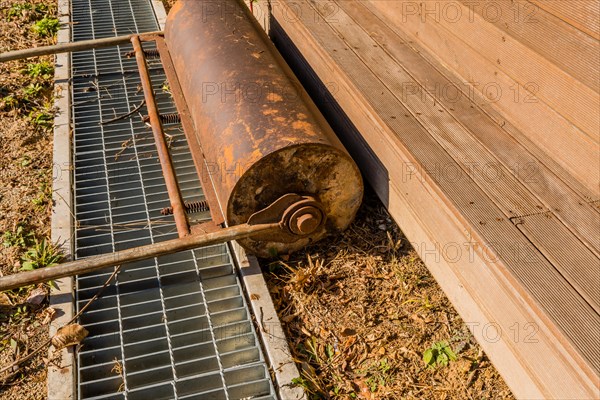 Hand pushed surface roller in front of wooden stadium benches at edge of dirt field