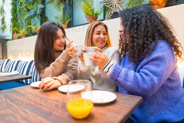 Three adult caucasian women talking happily in a colorful cafeteria