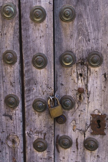 Antique wooden door with metal rivets and a padlock