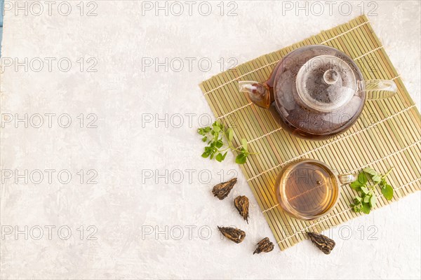 Red tea with herbs in glass on gray concrete background and linen textile. Healthy drink concept. Top view, flat lay, copy space