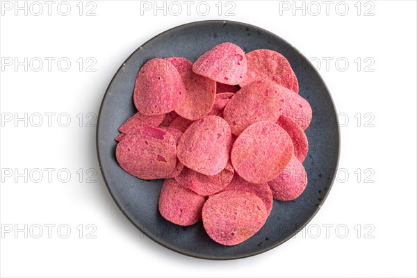 Red potato chips with herbs and tomatoes on blue cearmic plate isolated on white background. Top view, flat lay, close up