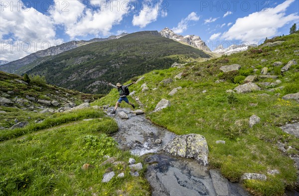 Mountaineer jumping over a mountain stream, Berliner Hoehenweg, Zillertal Alps, Tyrol, Austria, Europe