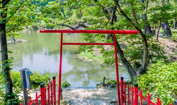 Torii Shinto gate under shade trees in Japanese garden in Hiroshima, Japan, Asia