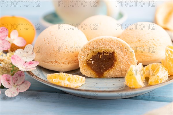 Japanese rice sweet buns mochi filled with tangerine jam and cup of coffee on a blue wooden background and linen textile. side view, close up, selective focus