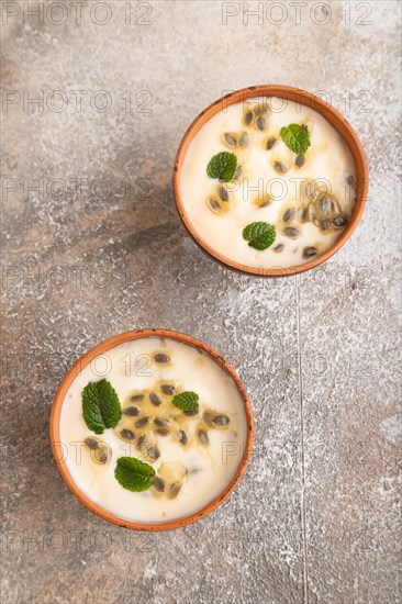 Yoghurt with granadilla and mint in clay bowl on brown concrete background. top view, flat lay, close up