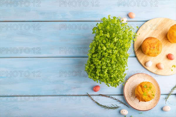 Homemade cakes with chocolate eggs and spinach microgreen on a blue wooden background. top view, flat lay, copy space