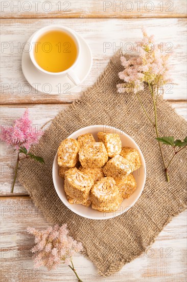 Traditional turkish delight (rahat lokum) in white ceramic plate with cup of green tea on a white wooden background. top view, flat lay, close up