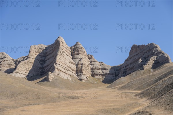 Mountain landscape with steep rocks, eroded rock formations between yellow hills, near Baetov, Naryn region, Kyrgyzstan, Asia