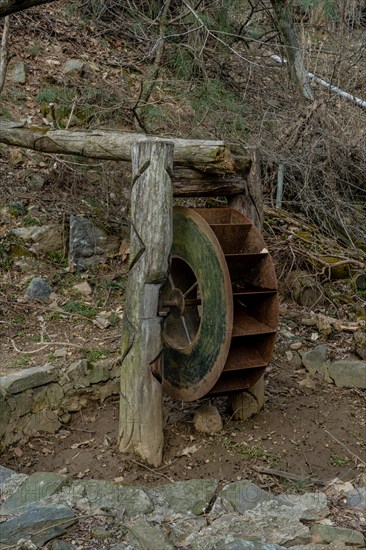 Old, rusted, metal waterwheel in mountainside public park