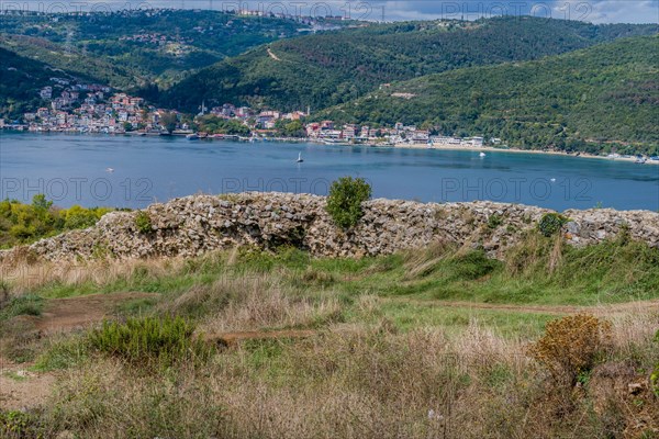 Remains of castle wall ruins with Bosphorus Strait and coastal village in background in Istanbul, Tuerkiye