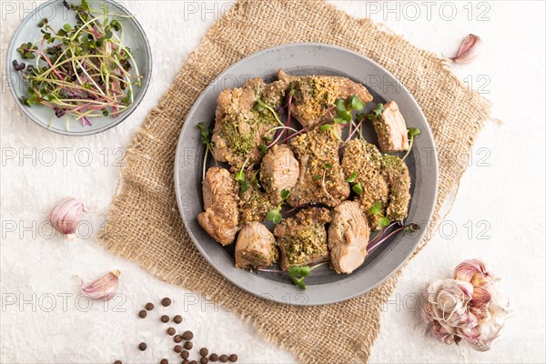 Stewed turkey fillet with garlic and sprouts of radish on white wooden background and linen textile. Top view, flat lay, close up