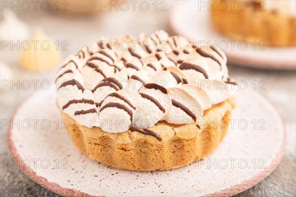 Two tartlets with meringue cream and cup of coffee on brown concrete background. side view, selective focus. Breakfast, morning, concept