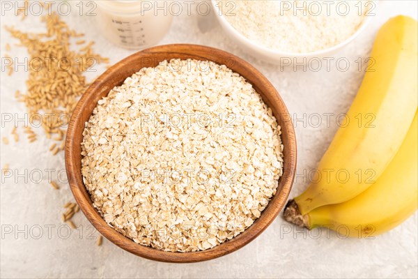 Powdered milk and oatmeal, banana baby food mix, infant formula, pacifier, bottle, spoon on gray concrete background. Top view, flat lay, artificial feeding concept