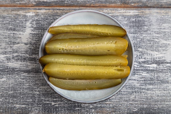 Marinated cucumber on a blue ceramic plate on a gray wooden background. Top view, flat lay, close up