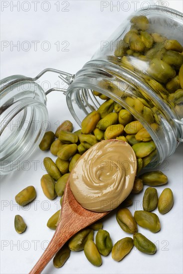 Pistachios with glass container and spoon with pistachio cream, pistachio