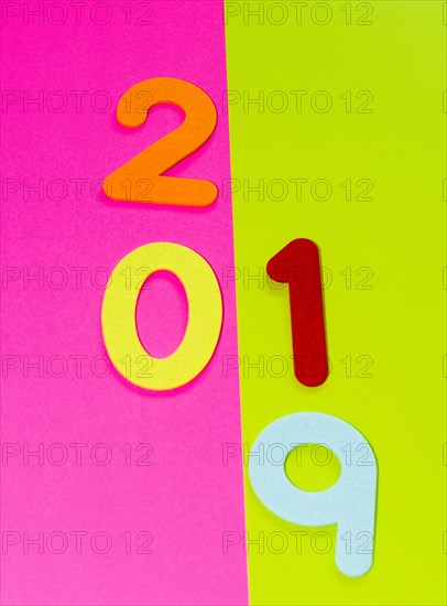 The numbers 2019 made of felt of different colors photographed on pink and yellow background