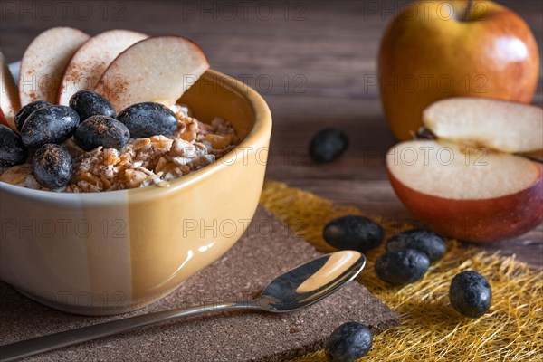 Healthy muesli with blue grapes and apple slices in a yellow bowl