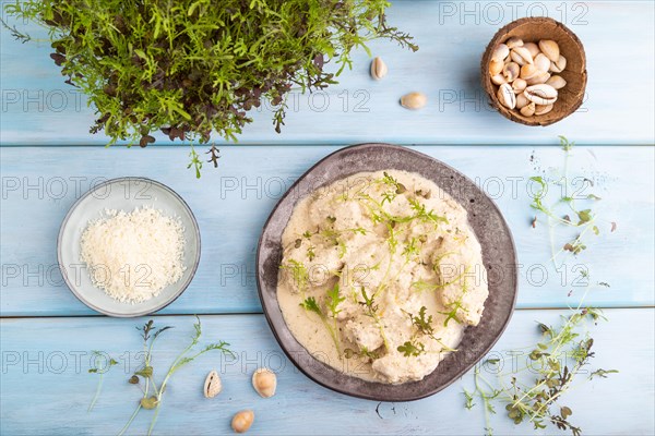 Stewed chicken fillets with coconut milk sauce and mizuna cabbage microgreen on blue wooden background. top view, flat lay, close up