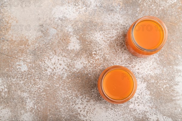 Baby puree with fruits mix, pumpkin, persimmon, mango infant formula in glass jar on brown concrete background. Top view, flat lay, copy space, artificial feeding concept
