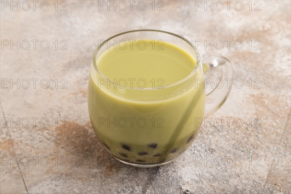 Bubble tea with pistachio and caramel in glass on brown concrete background. Healthy drink concept. Side view, close up
