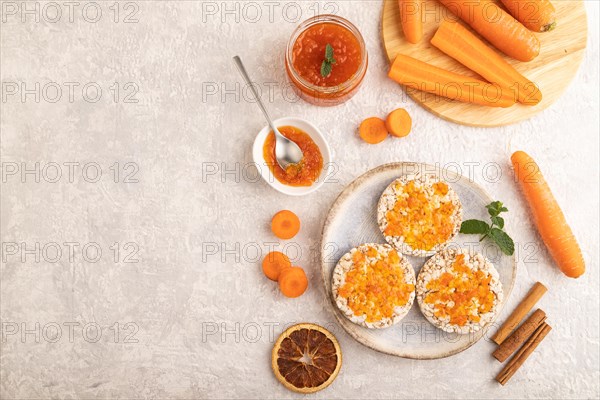 Carrot jam with puffed rice cakes on gray concrete background. Top view, flat lay, copy space