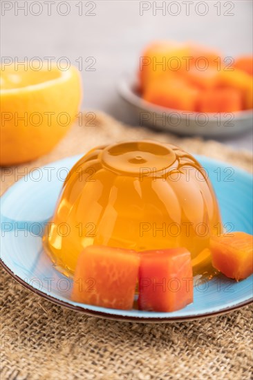 Papaya and orange jelly on gray concrete background and linen textile. side view, close up, selective focus