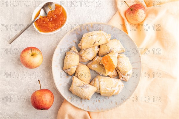 Homemade sweet cookie with apple jam and cup of coffee on gray concrete background and orange linen textile. top view, flat lay, close up